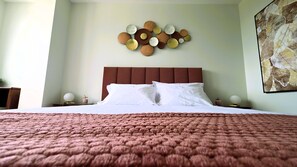 Ein Bett mit braunem Kopfteil, weißer Bettwäsche und einer gebrauchten, rosa Decke.