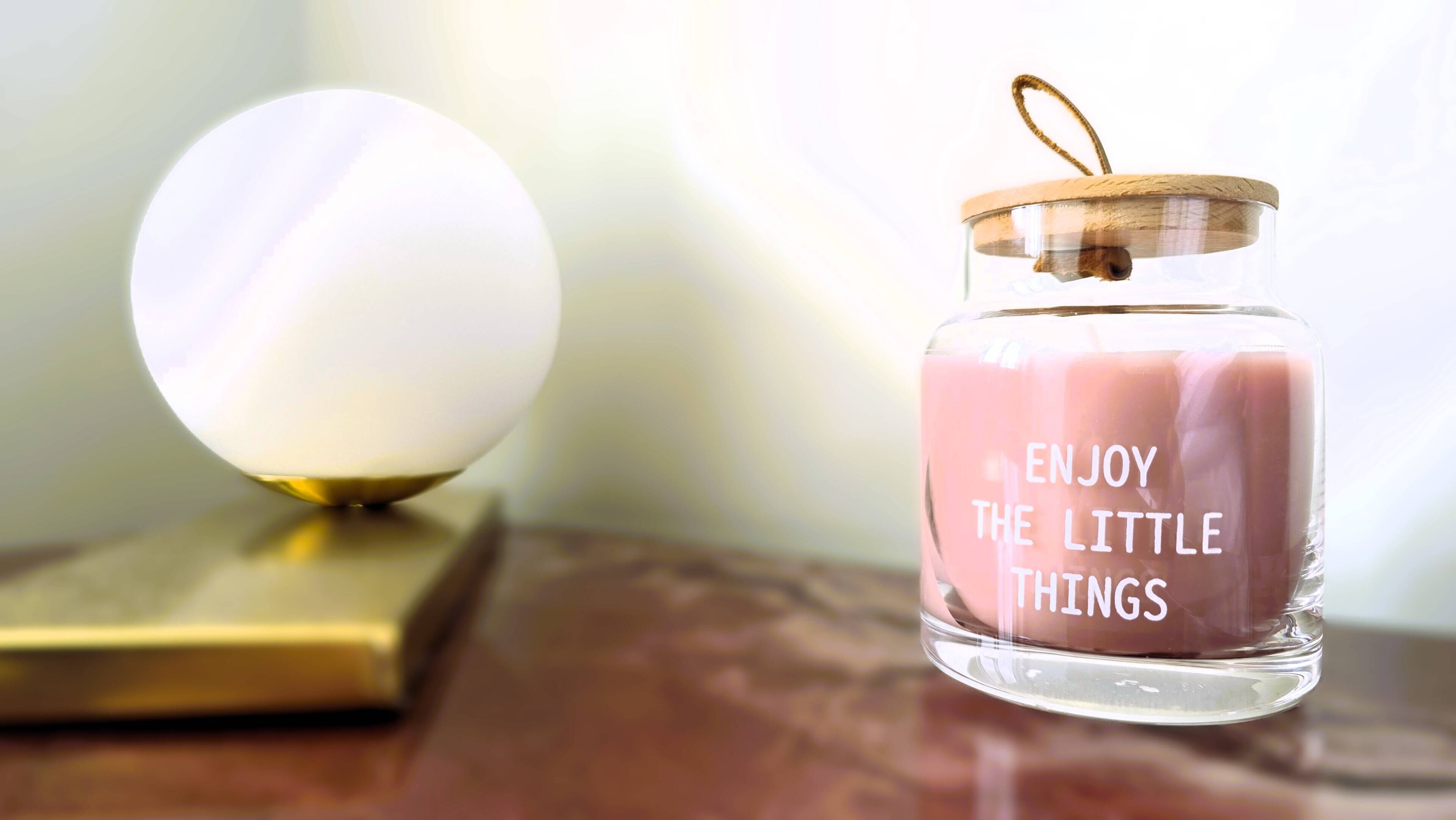 A clear glass jar with a lid and a message, placed on a wooden surface.