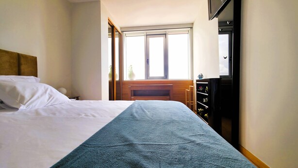 Et hotelværelse med seng, skrivebord og fjernsyn.