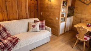 Un intérieur chaleureux, avec des éléments en bois, comprenant un canapé, une table à manger et un coin cuisine.