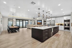 A modern kitchen with a large island, built-in appliances, and a dining area with a view.