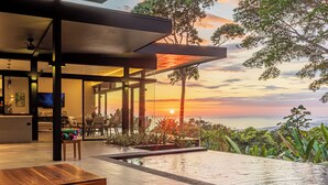 A modern outdoor area with a pool, seating, and a view of the sunset. - Brand-New Ocean View Home at a Special Rate (Piedra Amarilla)