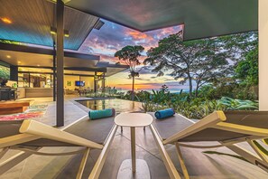 Un espacio moderno para sentarse al aire libre con vista al atardecer y árboles.