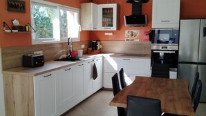 Una cocina moderna con armarios blancos, una mesa de comedor de madera, sillas negras y un horno empotrado.