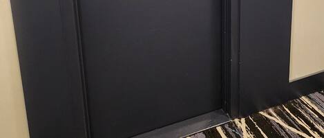 Una puerta oscura con manija y cerradura doradas, y el número '1609' en la pared a la derecha.