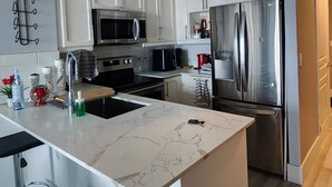 A modern kitchen with white cabinets, stainless steel appliances, a marble island, and pendant lighting. - 2-bedroom apartment in amazing Toronto with cool AC breeze (Toronto)