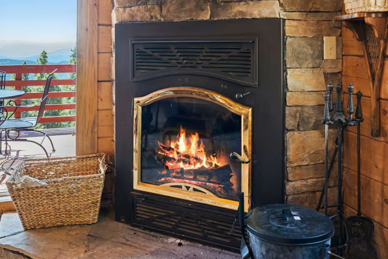 Una chimenea de piedra con fuego, una cesta de mimbre y una olla de metal.