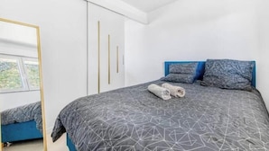 Een slaapkamer met een bed, een spiegel, een kledingkast en een raam.