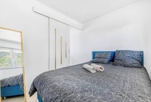 A bedroom with a bed, a mirror, a wardrobe, and a window.