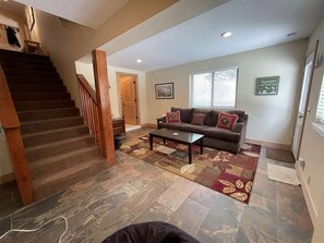 A living room with a staircase, a sofa, a coffee table, and a patterned rug. - Awesome 4-bedroom house in Mammoth Lakes perfect for your getaway (Mammoth Lakes)