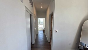 A hallway with wooden flooring, white walls, and doors leading to other rooms.