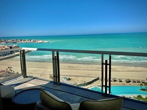 A balcony with a view of the beach, a pool, and a distant pier. - Beachfront Studio at Sonoran Star Resort | Stunning Ocean Views (Puerto Peñasco)
