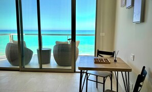 A room with a large sliding glass door leading to a balcony with wicker furniture and a view of the ocean. - Beachfront Studio at Sonoran Star Resort | Stunning Ocean Views (Puerto Peñasco)