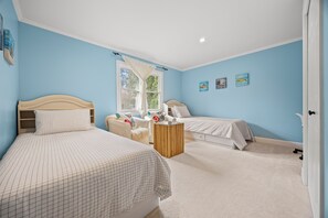Un dormitorio con dos camas, una ventana con cortina blanca y una obra de arte en la pared.