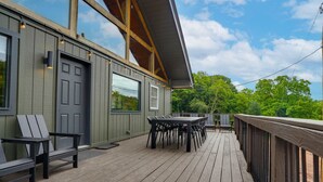 A wooden deck with outdoor furniture, a covered area with a door, and a view of trees. - Pickleball, Sauna, Hot Tub, Cold Plunge, Game Room, Pond, Mini Golf (Broad Top City)