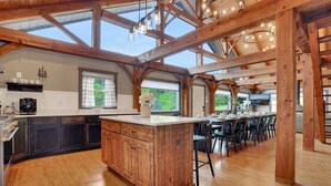 A spacious kitchen with a large island, wooden beams, and a dining area with multiple chairs. - Pickleball, Sauna, Hot Tub, Cold Plunge, Game Room, Pond, Mini Golf (Broad Top City)