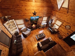 A cozy cabin interior with a fireplace, wooden walls, a sofa, a chair, and a television. - Secluded 1BR Cabin with Hot Tub, Wifi and Private Koi Pond (Turtletown)