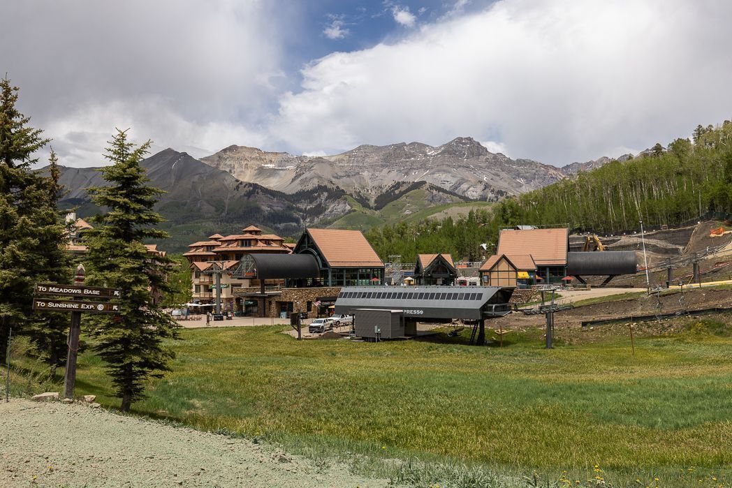 Una località montana con edifici, un segnale stradale e un binario ferroviario.