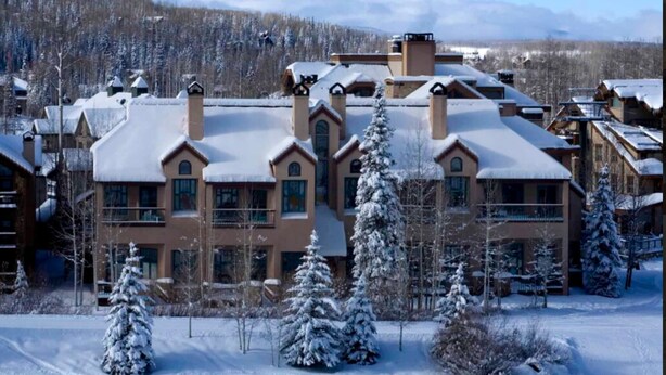 A large, multi-story building with a symmetrical facade, multiple chimneys, and snow-covered surroundings. - Ski/Bike-In Out | Gondola Steps | Mtn Village Core (Mountain Village)