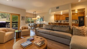A modern living room with a sofa, coffee table, and chairs, a dining area with a table and chairs, and a kitchen with wooden cabinets and appliances. - Ski/Bike-In Out | Gondola Steps | Mtn Village Core (Mountain Village)