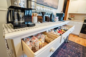 A kitchen with a coffee machine, tea kettle, and a drawer with food items. - Game Room + Coffee Bar | Near Dining, Parks & Mall (Overland Park)