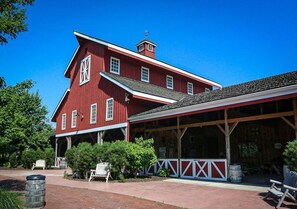 A red barn with a covered porch and a white fence. - 2nd Lounge + Coffee Bar | 20 Min to Kansas City (Overland Park)