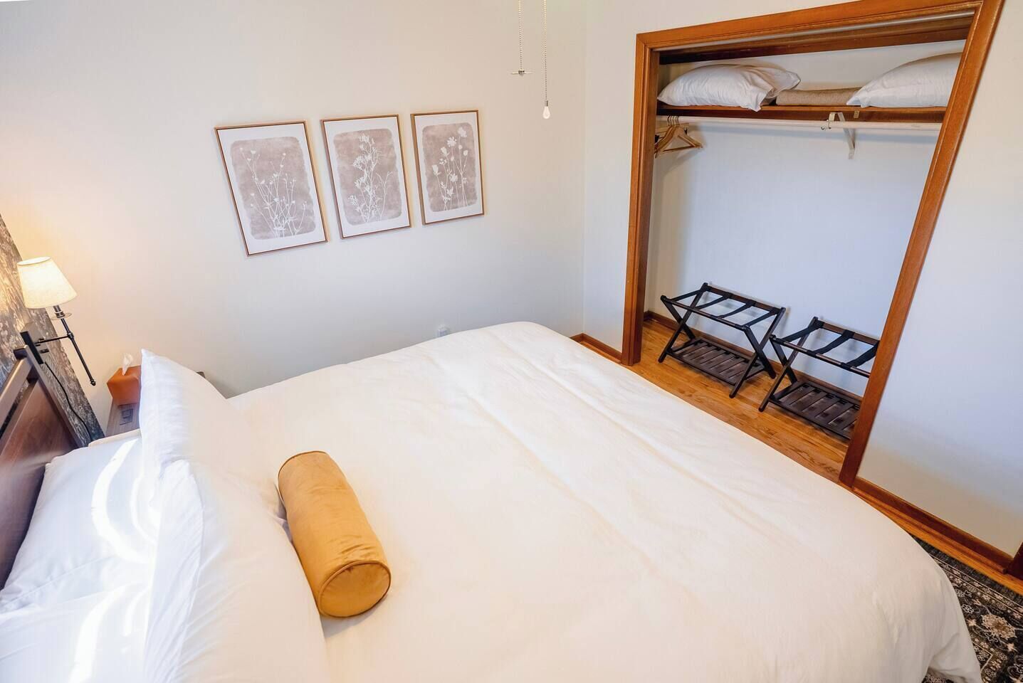 Una habitación de hotel con una cama, un armario de madera y tres cuadros en la pared.