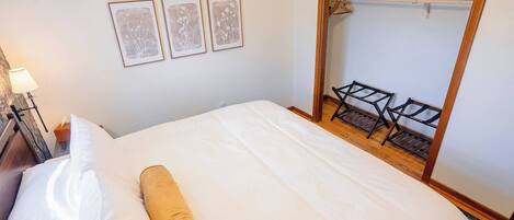 Una habitación de hotel con una cama, un armario de madera y tres cuadros en la pared.