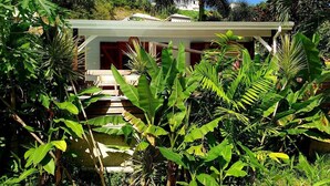 Una casa con una escalera que conduce a una puerta roja, rodeada de abundante vegetación.
