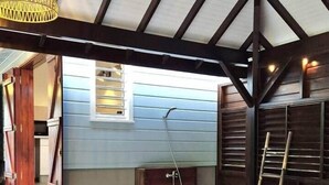 Un espacio al aire libre cubierto con un banco de madera, una lámpara colgante y una ducha.