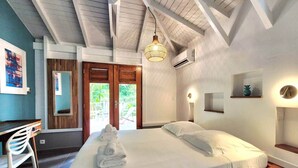Un dormitorio con cama, escritorio y silla. Hay una puerta que da a un espacio al aire libre.