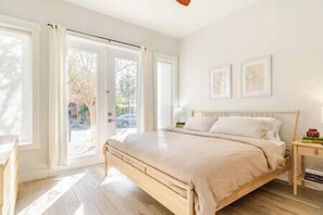 A bedroom with a bed, a nightstand, and a window with curtains.
