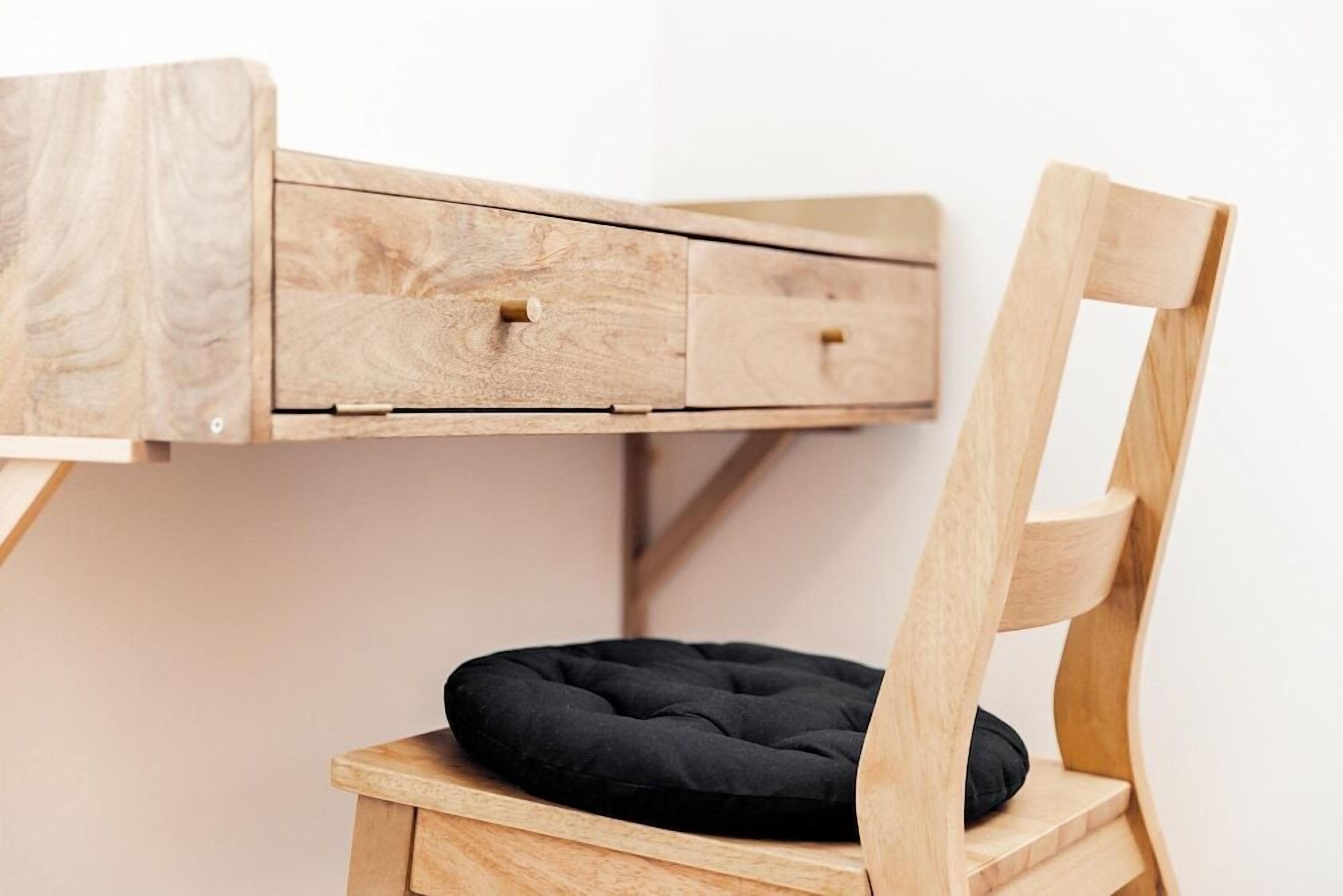 A wooden desk with two drawers and a cushioned chair.