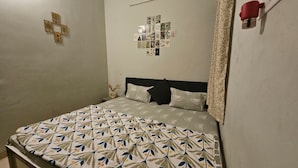 Une chambre avec un lit, un mur orné d’une décoration en forme de croix et un autre mur recouvert d’un collage de photos.