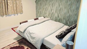 Ein Schlafzimmer mit Bett, Wandgerät zur Klimatisierung, Vorhängen und einer Wand mit Muster.