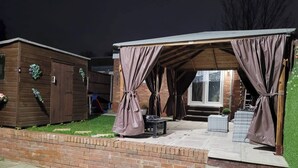 Eine überdachte Terrasse im Freien mit einer Ziegelwand, einem Holler Schuppen und einem Fenster.