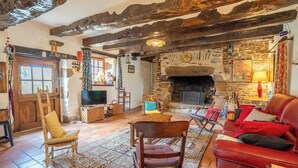 A rustic interior with exposed wooden beams, a stone fireplace, and traditional furnishings. - Maison bretonne de 1600 : Authenticité & Sérénité (Inzinzac-Lochrist)