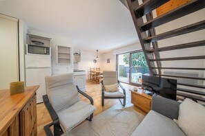 A modern kitchen with built-in appliances, a dining area with a table and chairs, and a living area with a sofa and TV.