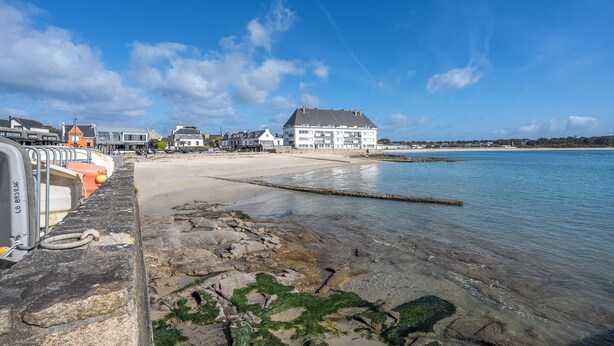 A coastal view with a sandy beach, a pier with boats, and a building with a sloped roof. - Sea-view garden-level flat (Ploemeur)
