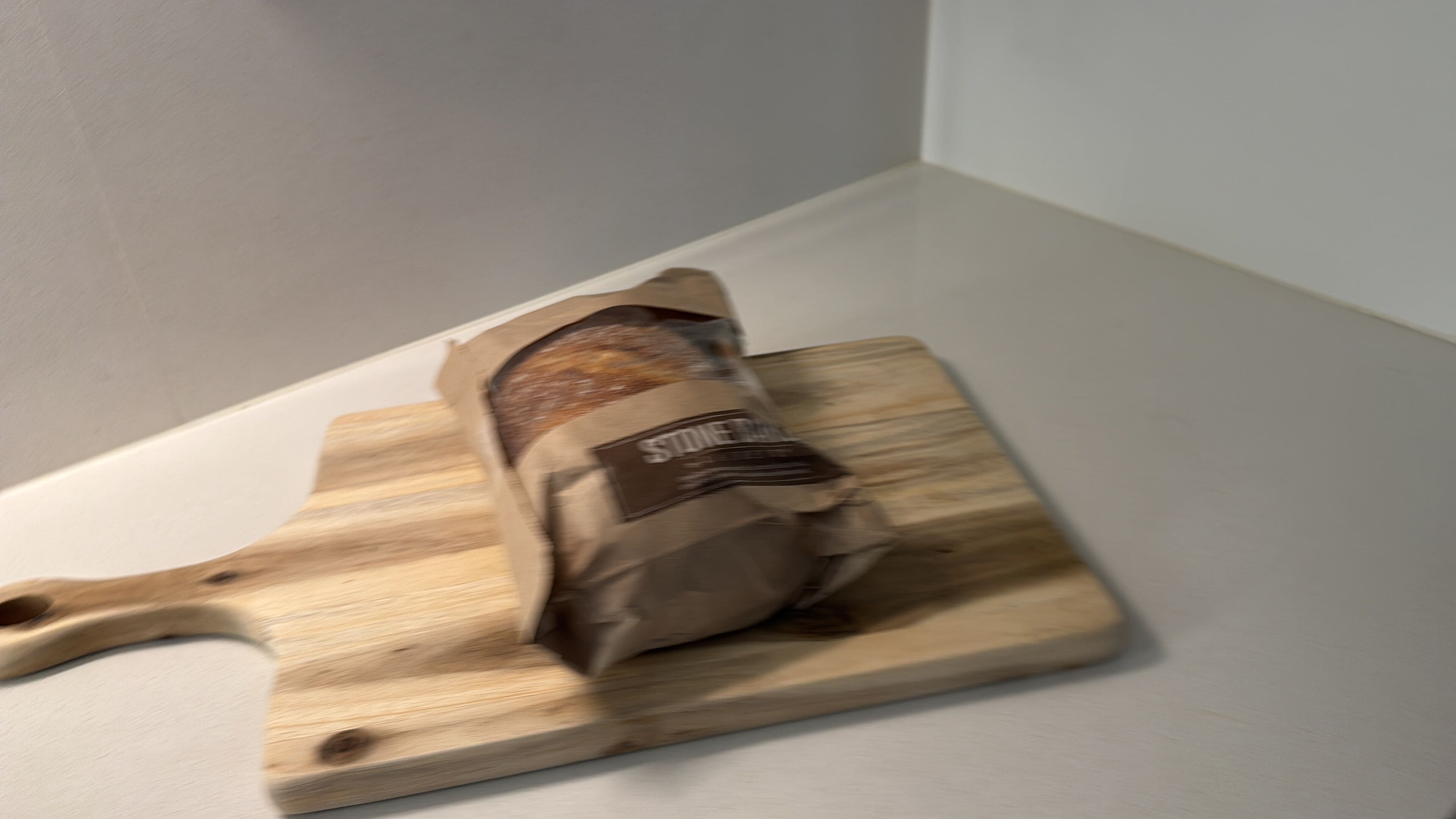 Een houten snijplank met een pak grof gemalen zout erop.