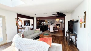 Ein Wohnzimmer mit einer Couch, einem Fernseher und einem Essbereich mit Stühlen und einem Tisch.