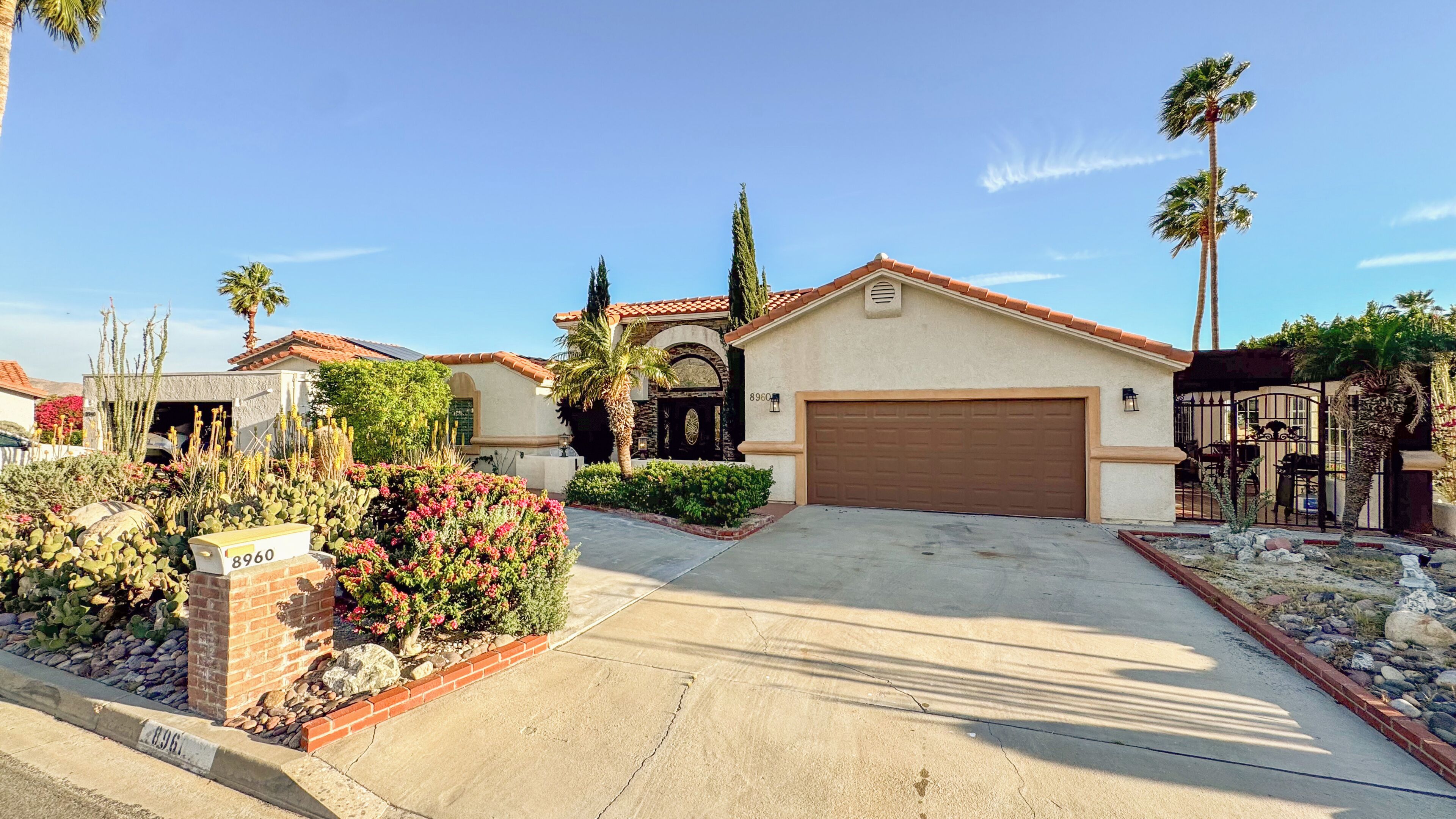 A residential house with a garage, a driveway, and a well-maintained garden with cacti and flowers.