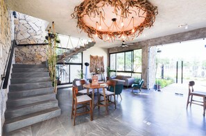 A modern interior with a stone staircase, a chandelier, and a seating area with a view.