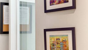 Eine Tür mit einer Schwarzwerttafel, zwei gerahmte Kunstwerke an der Wand und ein weißes Klimagerät.