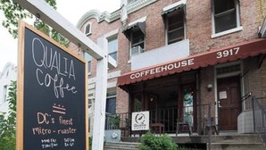 Ein Gebäude mit einem Schild, auf dem 'QUALITY Coffee' und 'DC's finest micro-roaster' sowie die Öffnungszeiten stehen.