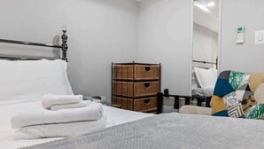 Ein ordentlich bezogenes Bett mit weißen Handtüchern, einer hölzernen Kommode und einem Spiegel an der Wand.