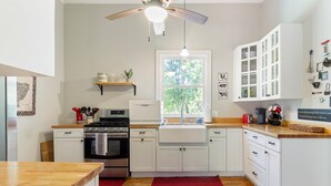 Una cocina moderna con armarios blancos, horno empotrado, lavabo y ventilador de techo.