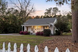 A single-story house with a front porch, surrounded by a white picket fence and a well-maintained lawn. - Farmhouse | Deck Space | Close to downtown (Wilmington)
