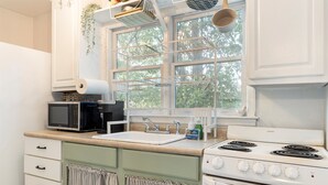 A kitchen with a stove, microwave, sink, and cabinets.