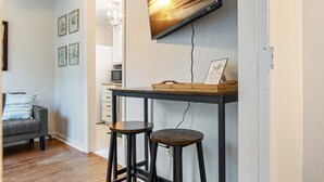 A modern living room with a sofa, a TV mounted on the wall, and a desk with stools.